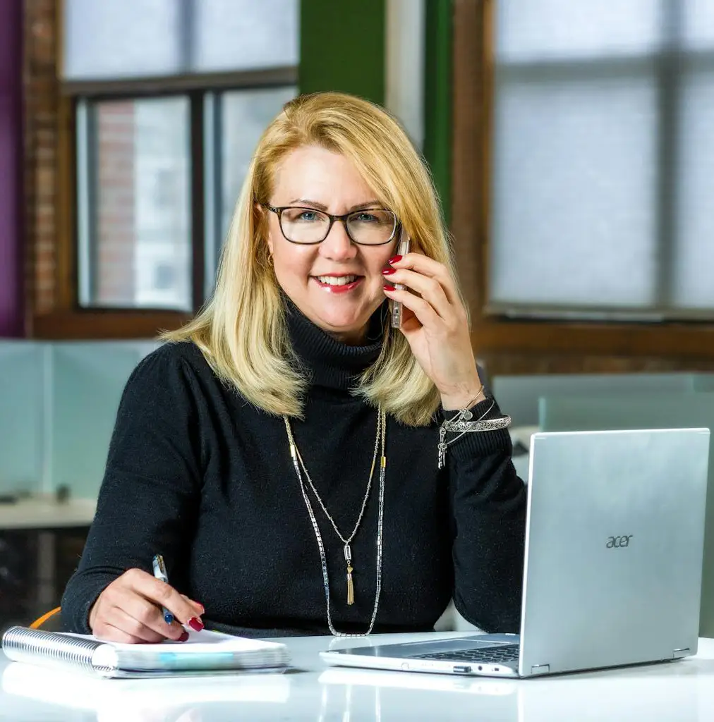 Une femme tenant un téléphone devant un pc portable